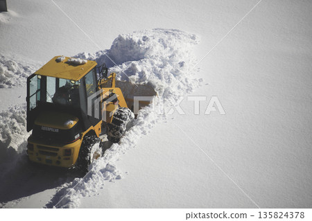 Snow removal vehicle clearing a snow-covered parking lot Snow removal vehicle clearing a snow-covered parking lot 135824378