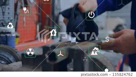 Technician wearing coveralls wiping workpiece in workshop, vise, tools and energy icons, copy space Technician wearing coveralls wiping workpiece in workshop, vise, tools and energy icons, copy space 135824762