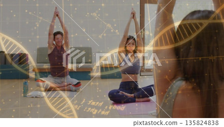 Stretching Asian woman in sportswear raising arms overhead in yoga studio, with water bottle, towel 135824838