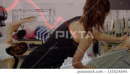 Reaching woman in black workout clothes holding foot on mat at Pilates studio, with stability balls Reaching woman in black workout clothes holding foot on mat at Pilates studio, with stability balls 135824849