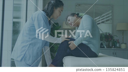 Leaning physiotherapist placing hands on patient knee joint on therapy table in therapy room Leaning physiotherapist placing hands on patient knee joint on therapy table in therapy room 135824851