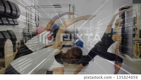 Guiding pilates instructor wearing leggings doing side stretch on reformers in studio with barrels Guiding pilates instructor wearing leggings doing side stretch on reformers in studio with barrels 135824859