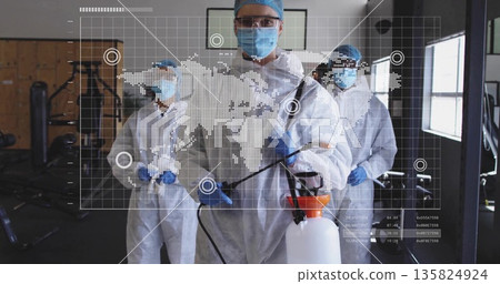 Spraying technicians disinfecting gym machines in gym, with sprayer and world map overlay 135824924