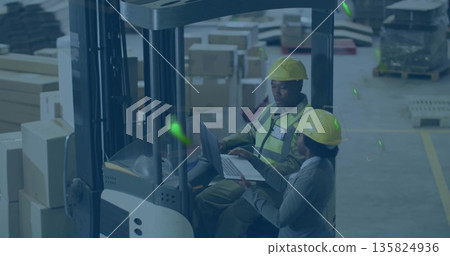 Forklift operator and coworker in safety gear reviewing inventory by forklift in depot, with laptop 135824936