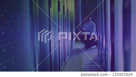 Kneeling African American technician inspecting server rack with LEDs in data center, with tablet Kneeling African American technician inspecting server rack with LEDs in data center, with tablet 135825020