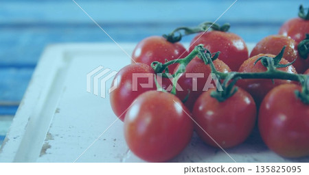 Cluster of cherry tomatoes sitting on white board at kitchen counter, with green stems and droplets Cluster of cherry tomatoes sitting on white board at kitchen counter, with green stems and droplets 135825095