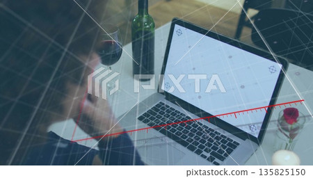 Man wearing dark top leaning over laptop dining table, with wine glass rose candle, copy space Man wearing dark top leaning over laptop dining table, with wine glass rose candle, copy space 135825150