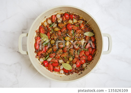Cooking a vegetable stew with tomatoes and herbs in a large pot on the kitchen counter 135826109