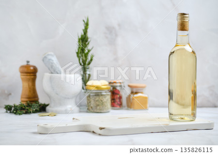 Bottle of oil with herbs and spices in a kitchen setting 135826115