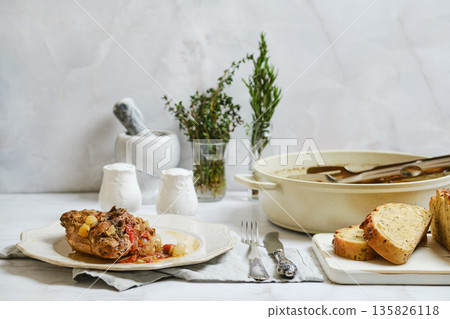 Cooking rabbit stew with seasonal vegetables and bread on a simple dining table 135826118