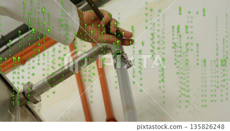 Technician's hand tightening hose clamp on pipe in utility room, with binary code, orange conduit Technician's hand tightening hose clamp on pipe in utility room, with binary code, orange conduit 135826248