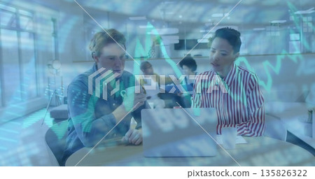 Viewing laptop and holding coffee mug, blue-shirted man analyzing financial data in office lounge 135826322