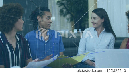 Reviewing papers on coffee table, colleagues in office lounge using laptop with folder, ceramic mug Reviewing papers on coffee table, colleagues in office lounge using laptop with folder, ceramic mug 135826340