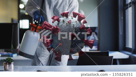 Spraying technician in suit and gloves targeting 3D virus model in office with disinfectant sprayer Spraying technician in suit and gloves targeting 3D virus model in office with disinfectant sprayer 135826351