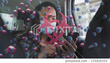 Tapping smartphone woman wearing blue mask in car back seat, with red biohazard and virus graphics Tapping smartphone woman wearing blue mask in car back seat, with red biohazard and virus graphics 135826355