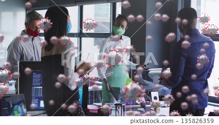 Gathering four masked coworkers discussing health measures in modern office, with monitors, divider 135826359