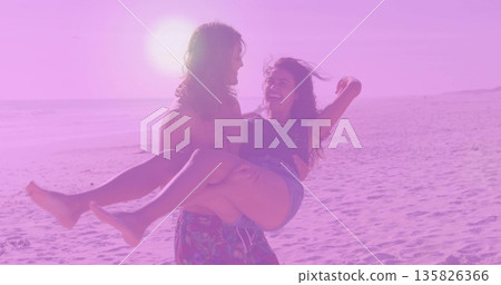 Shirtless man in floral trunks carrying woman in sleeveless top denim shorts along beach at sunset Shirtless man in floral trunks carrying woman in sleeveless top denim shorts along beach at sunset 135826366