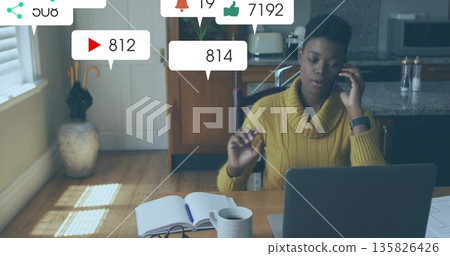 Calling content creator making notes on notebook at home kitchen table, with social media metrics Calling content creator making notes on notebook at home kitchen table, with social media metrics 135826426