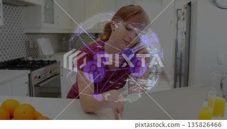 Typing woman handling teleconference call at kitchen island, with laptop smartphone overlay Typing woman handling teleconference call at kitchen island, with laptop smartphone overlay 135826466