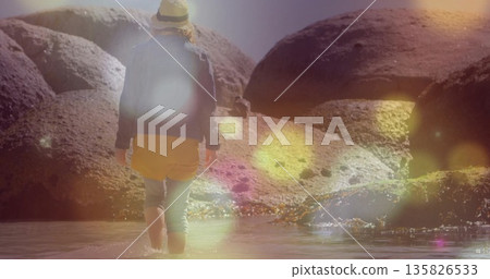 Wading woman wearing straw hat, mustard shorts, olive leggings and boots in shallow water, boulders 135826533