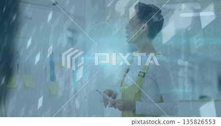 Analyzing woman in yellow overalls with tablet reviewing photos on glass wall in office, copy space Analyzing woman in yellow overalls with tablet reviewing photos on glass wall in office, copy space 135826553