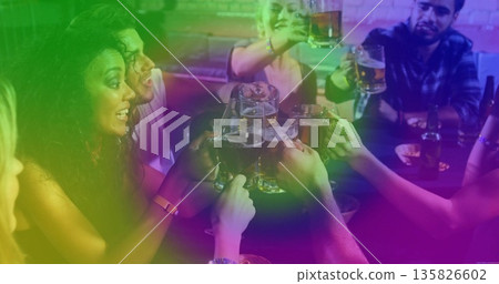 Clinking group of friends raising glass beer mugs in cozy pub, with snack plates and coasters Clinking group of friends raising glass beer mugs in cozy pub, with snack plates and coasters 135826602
