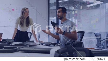 Presenting engineer holding tablet gesturing at drone prototypes in office with whiteboard sketches Presenting engineer holding tablet gesturing at drone prototypes in office with whiteboard sketches 135826621