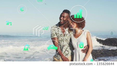 Smiling couple in patterned shirt and white dress leaning on sandy shoreline, with green eco icons 135826644