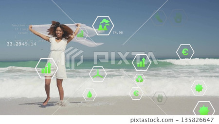 Woman standing holding white scarf overhead on beach shore, with green icons and code overlaying 135826647