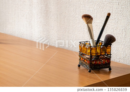 Makeup brush holder with cosmetic brushes on dresser for beauty care. Beauty tools and accessory for makeup artist at home or salon. copy space 135826839