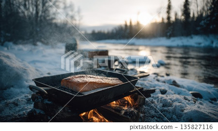 Salmon fillet cooking over open fire in a snowy winter landscape Salmon fillet cooking over open fire in a snowy winter landscape 135827116