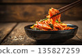 Traditional Korean kimchi picked by chopsticks from a dark bowl 135827259