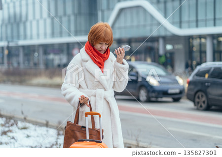 Winter travel woman walking in snowy european city with suitcase. Holiday vacation trip abroad, urban cityscape, solo female traveler during cold season, travel and tourism concept. 135827301