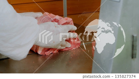 Guiding butcher in coat feeding raw meat through bandsaw inside cutting room, digital map overlay 135827374