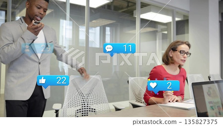 Presenting man wearing suit speaking into mic at conference table with floating social media icons 135827375