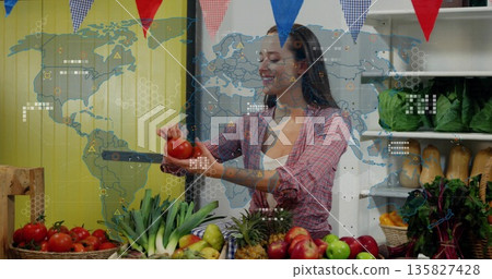 Market vendor weighing ripe tomato on metal scale in farmers' stall, with produce and bunting flags Market vendor weighing ripe tomato on metal scale in farmers' stall, with produce and bunting flags 135827428