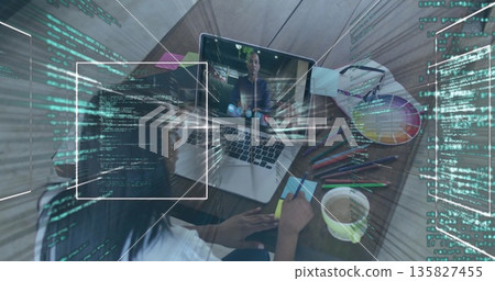 Writing designer jotting note at desk during call, with laptop, supplies, code overlays, copy space 135827455