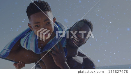 Lifting adult male carrying child on shoulders at sandy beach, with striped beach towel Lifting adult male carrying child on shoulders at sandy beach, with striped beach towel 135827478