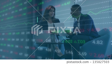 Discussing mid adult colleagues reviewing market charts in corporate lounge, with laptop and tablet 135827503