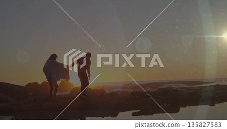 Couple holding hands walking on rocky shoreline at sunset, wrap, tide pools, lens flare, copy space Couple holding hands walking on rocky shoreline at sunset, wrap, tide pools, lens flare, copy space 135827583