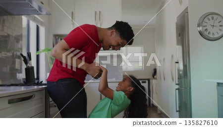Playing parent and child holding hands in modern kitchen, with gas range and potted plant Playing parent and child holding hands in modern kitchen, with gas range and potted plant 135827610