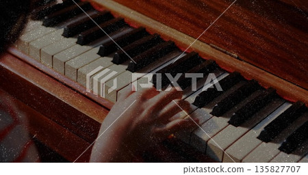 Chinese girl with striped sleeve pressing ivory and black keys in home studio, red felt strip 135827707