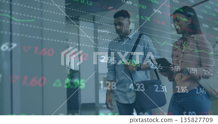 Walking colleagues carrying messenger bag and tablet in office corridor with stock market overlay 135827709