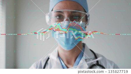 Doctor wearing protective gear analyzing real-time data in exam room, with stethoscope, goggles 135827719