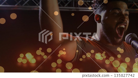 Adult singer raising arm, singing on stage under truss with microphone and bokeh lights, copy space Adult singer raising arm, singing on stage under truss with microphone and bokeh lights, copy space 135827742