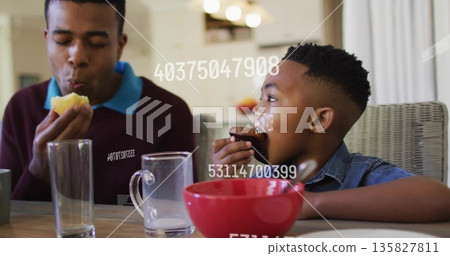 Eating father and son biting muffin and chocolate cupcake at wooden table, with overlaid numbers 135827811