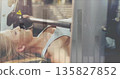 Female athlete in sports bra and gloves bench pressing on machine in gym, with digital overlay 135827852