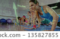 Woman in blue tank top planking on blue mats in gym, with chart overlay, copy space 135827855