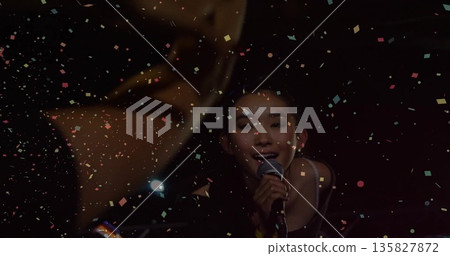 Performing female vocalist singing into wired microphone on stage with confetti, brass, copy space 135827872