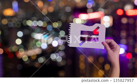 Hand holding torn paper with a cutout not equal sign symbol against a blurred night city bokeh background. Concept of social inequality, unfairness, and protest in an urban setting 135827957